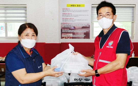 LG이노텍 노동조합 김동의 위원장(오른쪽)이 신종 코로나바이러스 감염증(코로나19) 피해 소상공인과 취약계층 지원을 위해 주문한 음식을 건네받고 있다. 사진=LG이노텍