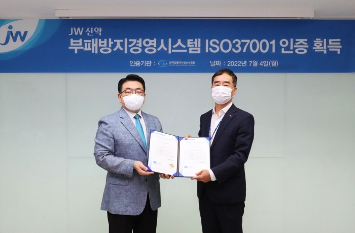 백승호 JW신약 대표이사(오른쪽)가 지난 4일 서울 서초동 본사에서 이원기 한국컴플라이언스인증원장에게 ISO37001 인증서를 받은 뒤 기념촬영을 하고 있다.