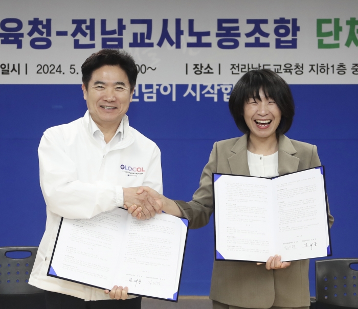 김대중 전남교육감(왼쪽)과 김신안 전남교사노조위원장이 8일 단체협약서를 들어 보이며 악수하고 있다.