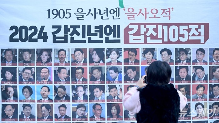 집회 참가자가 14일 오후 서울 국회의사당 인근에서 열린 '내란수괴 윤석열 즉각 탄핵 범국민촛불 大행진' 집회에서 윤 대통령 탄핵 투표 불참한 국민의힘 105명 관련 현수막을 살펴보고 있다. 사진=강민석 기자 kms@newsway.co.kr