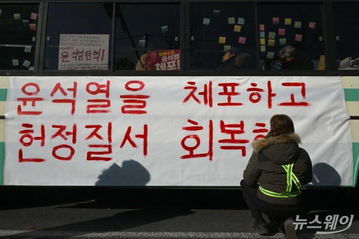 집회 참가자가 14일 오후 서울 국회의사당 인근에서 열린 '내란수괴 윤석열 즉각 탄핵 범국민촛불 大행진' 집회에 마련된 윤 탄핵버스에서 '윤석열을 체포하고 헌정질서 회복하자' 중형 현수막에 문구를 작성하고 있다. 사진=강민석 기자 kms@newsway.co.kr