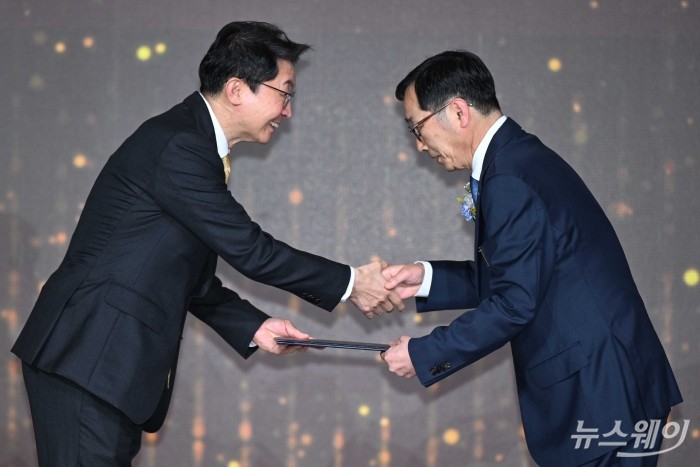 이억원 금융위원장이 31일 오후 서울 여의도 FKI타워에서 열린 회계의 날 기념식에서 김우현 SK하이닉스 부사장에게 산업포장을 수여한 뒤 악수를 하고 있다. 사진=강민석 기자 kms@newsway.co.kr