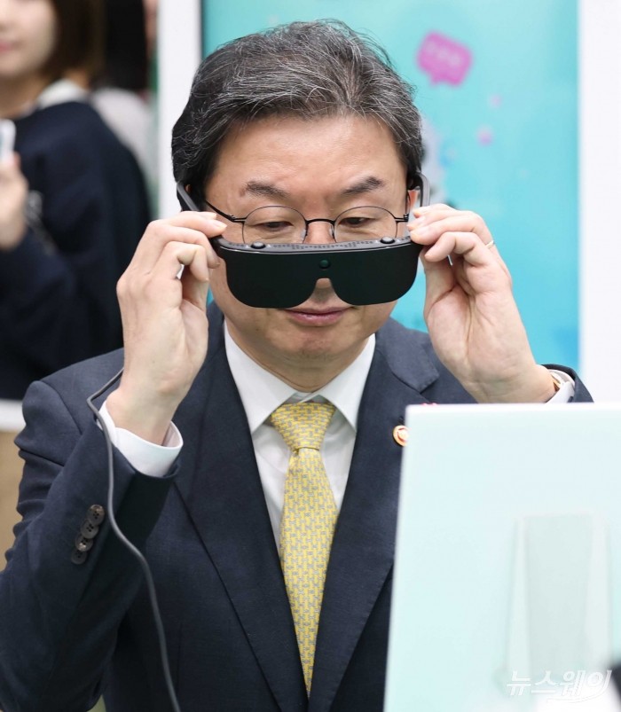 이억원 금융위원장이 26일 오전 서울 서초구 aT센터에서 열린 코리아 핀테크 위크 2025에서 하나은행금융그룹 부스를 찾아 AI 안경을 끼고 상품설명서를 보고 있다. 사진=강민석 기자 kms@newsway.co.kr