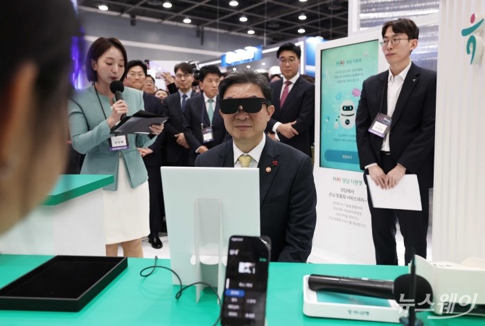 이억원 금융위원장이 26일 오전 서울 서초구 aT센터에서 열린 코리아 핀테크 위크 2025에서 하나은행금융그룹 부스를 찾아 AI 안경을 끼고 상품설명서를 보고 있다. 사진=강민석 기자 kms@newsway.co.kr