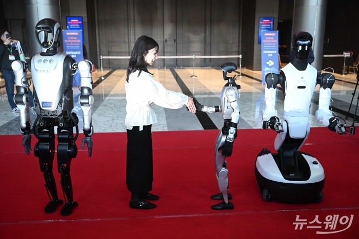 '2026 스마트공장·자동화산업전(AW 2026)'을 찾은 관람객이 4일 오전 서울 강남구 코엑스에서 중국 AI 휴머노이드 로봇 UNITREE 'G1'과 함께 인사를 하고 있다. (왼쪽 첫 번째)AGIBOT 'G2', (오른쪽 첫 번째)LEJU KUAVO '4 PRO'. 사진=강민석 기자 kms@newsway.co.kr