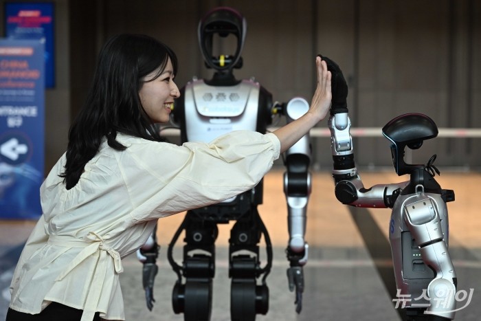 '2026 스마트공장·자동화산업전(AW 2026)'을 찾은 관람객이 4일 오전 서울 강남구 코엑스에서 중국 AI 휴머노이드 로봇 UNITREE 'G1'과 함께 인사를 하고 있다. 사진=강민석 기자 kms@newsway.co.kr