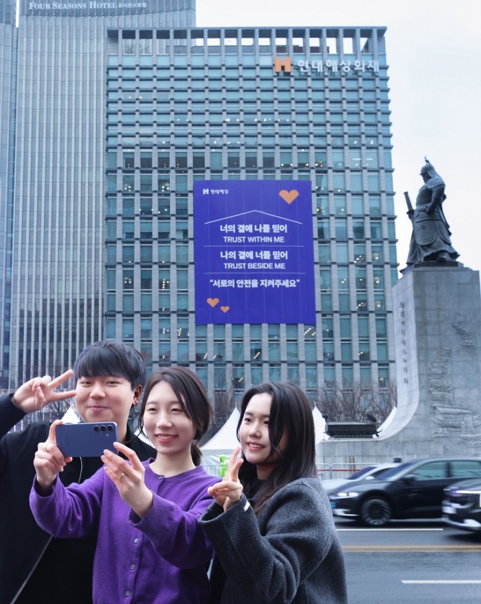 18일 서울시 종로구 현대해상 본사 외벽의 방탄소년단 노래 가사를 인용한 '신뢰와 안전' 메시지를 배경으로 외국인 방문객들이 사진을 촬영하고 있다. 사진=현대해상 제공