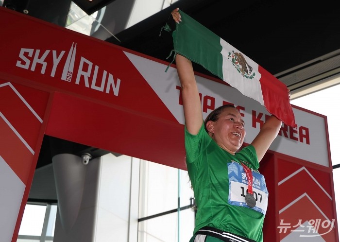 19일 오전 서울 송파구 롯데월드타워에서 열린 '2026 롯데월드타워 스카이런(SKY RUN)'에서 참가자가 멕시코 국기를 들고 결승선을 통과하고 있다. 사진=강민석 기자