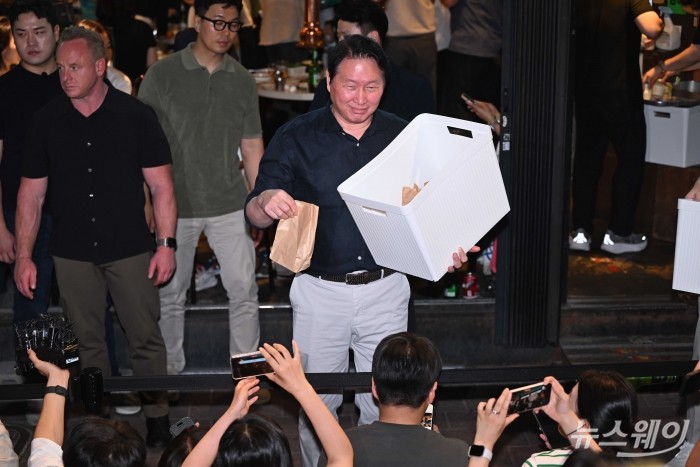 최태원 SK그룹 회장이 5일 오후 서울 마포구 형님저요 고깃집에서 '삼겹살 회동'을 즐기던 중 잠시 야외로 나와 준비한 선물을 시민들에게 전달하고 있다. 사진=강민석 기자