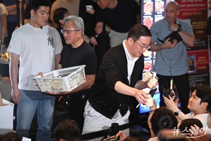 (왼쪽)젠슨 황 엔비디아 창립자 겸 최고경영자와 구광모 LG그룹 회장이 5일 오후 서울 마포구 형님저요 고깃집에서 최태원 SK그룹 회장, 이해진 네이버 의장과 함께 '삼겹살 회동'을 하던 중 잠시 야외로 나와 시민들에게 준비한 선물을 전달하고 있다. 사진=강민석 기자