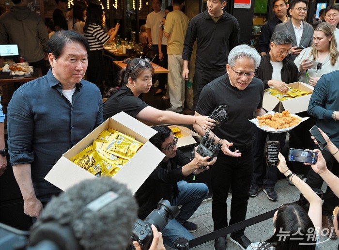 젠슨 황 엔비디아 최고경영자(CEO)와 최태원 SK그룹 회장이 7일 서울 강남구 깐부치킨에서 열린 '치맥 회동'중 밖으로 나와 취재진에게 음식을 나눠주고 있다. 사진=이수길 기자