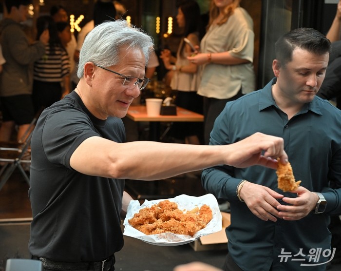 젠슨 황 엔비디아 최고경영자(CEO)와 최태원 SK 회장이 7일 서울 강남구 깐부치킨에서 열린 '치맥 회동'중 밖으로 나와 취재진에게 음식을 나눠주고 있다. 사진=이수길 기자