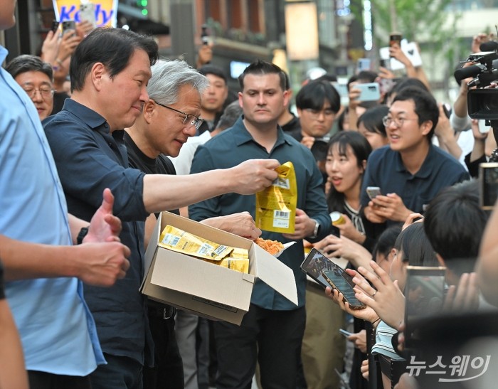 젠슨 황 엔비디아 최고경영자(CEO)와 최태원 SK그룹 회장이 7일 오후 서울 강남구 깐부치킨에서 열린 '치맥 회동'중 잠시 야외로 나와 시민들에게 'HBM 칩스'와 치킨 조각을 선물해주고 있다. 사진=이수길 기자