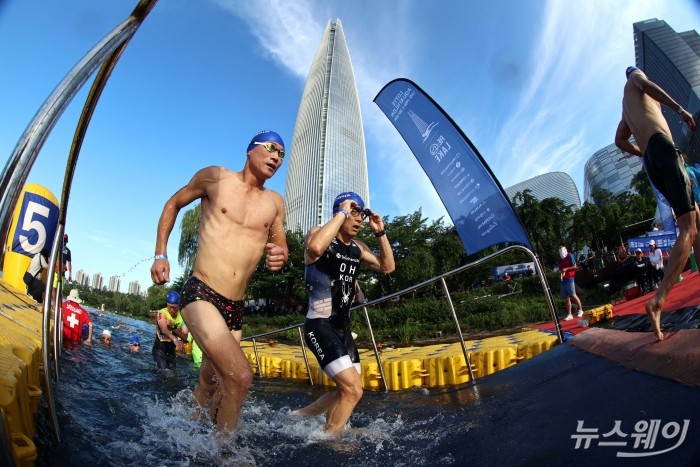 12일 오전 서울 송파구 잠실 석촌호수에서 열린 '2026 롯데 아쿠아슬론(2026 LOTTE AQUATHLON)'에서 참가자들이 롯데타워로 향하고 있다. 사진=강민석 기자