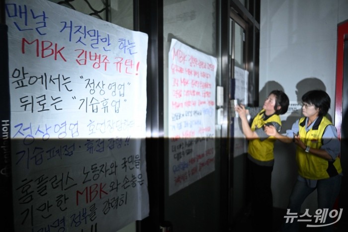 민주노총 서비스연맹 마트산업노동조합이 14일 오후 서울 강서구 홈플러스 본사 앞에서 열린 MBK의 일방적 면담 취소 규탄 및 노동조합 입장발표 기자회견을 마친 뒤 출입구에 항의 대자보를 부착하고 있다. 사진=강민석 기자