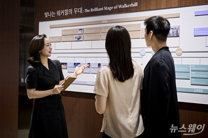 워커힐 호텔앤리조트 직원이 14일 서울 광진구 비스타 워커힐 로비에 마련된 브랜드 헤리티지와 미래 비전을 담은 브랜드 경험 공간 '워커힐 스토리 라운지'에서 방문객들에게 전시 콘텐츠를 소개하고 있다. 사진=워커힐 호텔앤리조트
