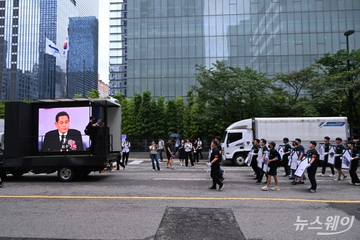 삼성전자 DX(디바이스경험) 부문 중심 노동조합 '동행'이 21일 오후 서울 서초구 삼성전자 사옥 일대에서 DS부문과의 보상 격차 해소를 요구하며 행진하는 가운데, 고(故) 이건희 회장의 1993년 삼성그룹 창립 55주년 및 제2창업 5주년 연설 영상이 송출되고 있다. 사진=강민석 기자